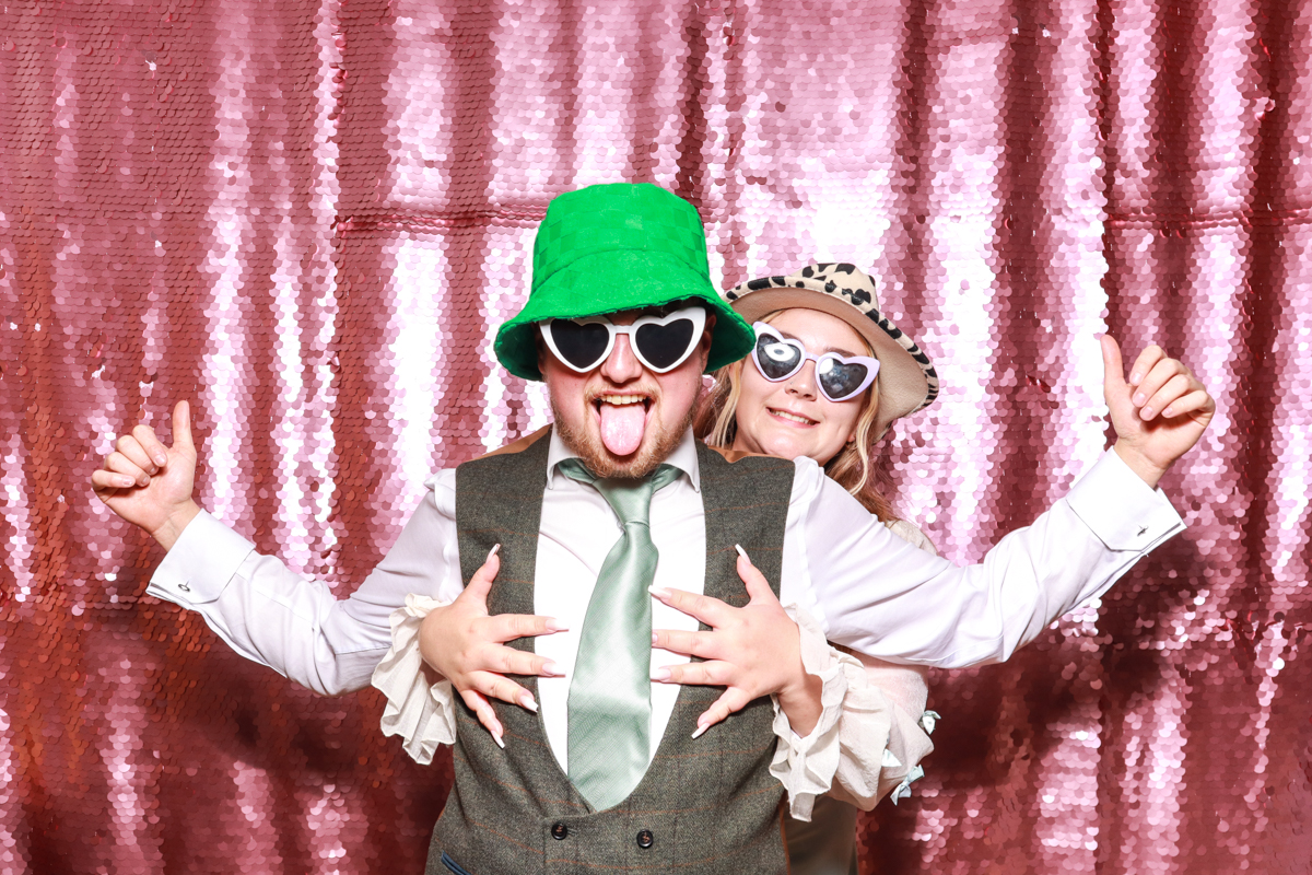 2 guests posing in a funny way at The Wood Norton Wedding reception during the party entertainment with mad hat photo booth hire
