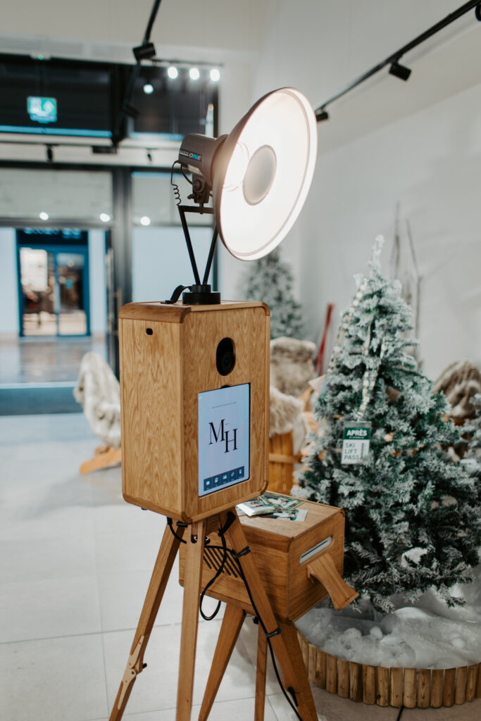 Apres ski style photo booth at Cotswolds Designer Outlet with skis, faux snow and cosy winter decor, with a Christmas shopping centre photobooth, Mad Hat Photo Booth