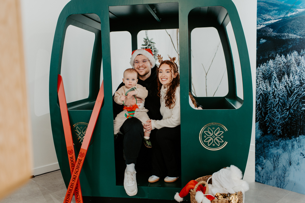 Family posing in an apres ski themed photo booth at Cotswolds Designer Outlet with festive props and instant prints