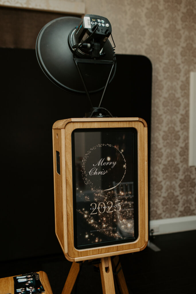Front view of the Icon photo booth with “Merry Christmas 2025” display on the screen, set up for a festive company event.
