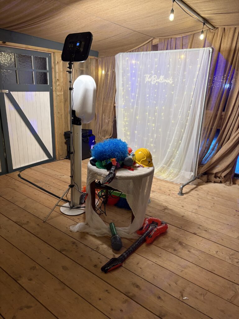 Ipad booth selfie pod rental setup for a very intimate wedding with a custom white backdrop and a few props on a small round table next to the pod