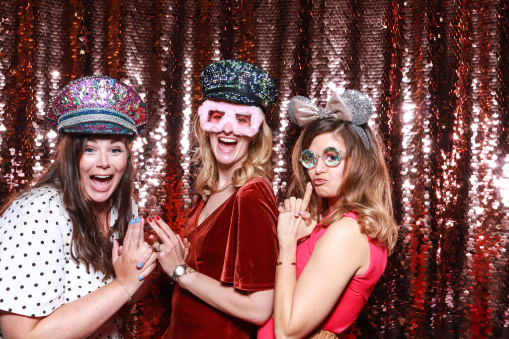 3 ladies posing like charlies angels, for a photobooths for events hire in the cotswolds, with party props and sequins backdrop
