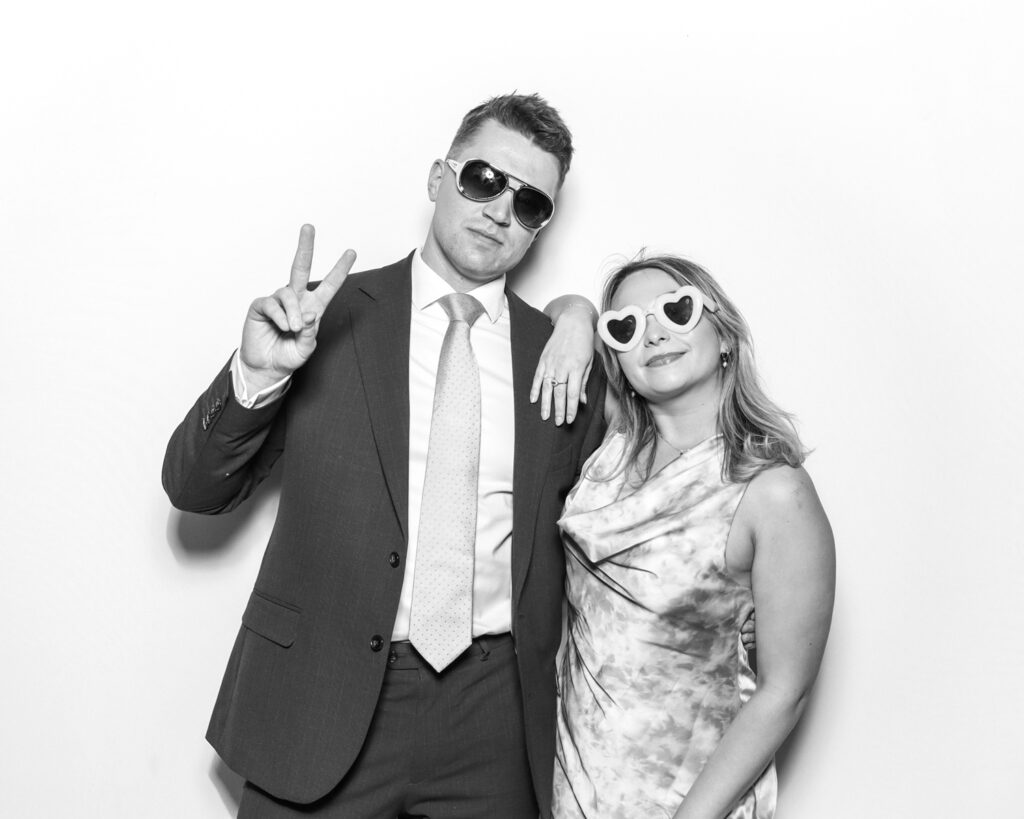 couple wearing party props posing against a white backdrop, for a kardashian glam booth rental in the cotswolds