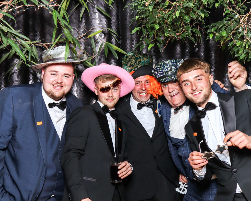large group of guests posing against a black sequins backdrop during a corporate event entertainment in Gloucester