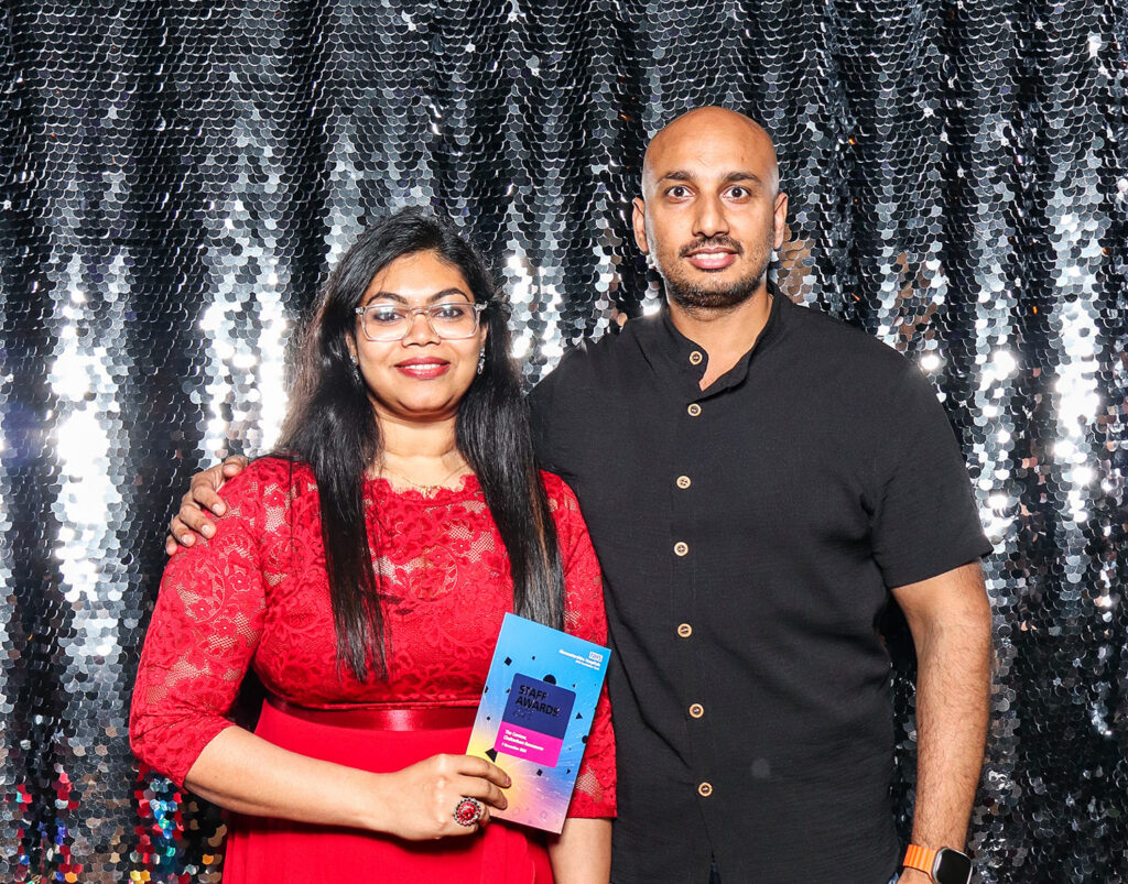 2 guests dressed elegantly during a Charity Gala Photo Booth Hire event entertainment posing against a silver sequins backdrop for a corporate event