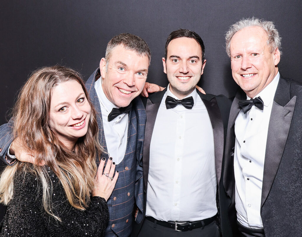 4 guests dressed elegantly during a Charity Gala Photo Booth Hire event entertainment posing against a black backdrop for a professional image during a corporate event4