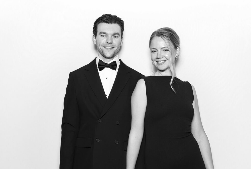 2 guests dressed elegantly during a Charity Gala Photo Booth Hire event entertainment posing against a white backdrop for a b&w image during a corporate event
