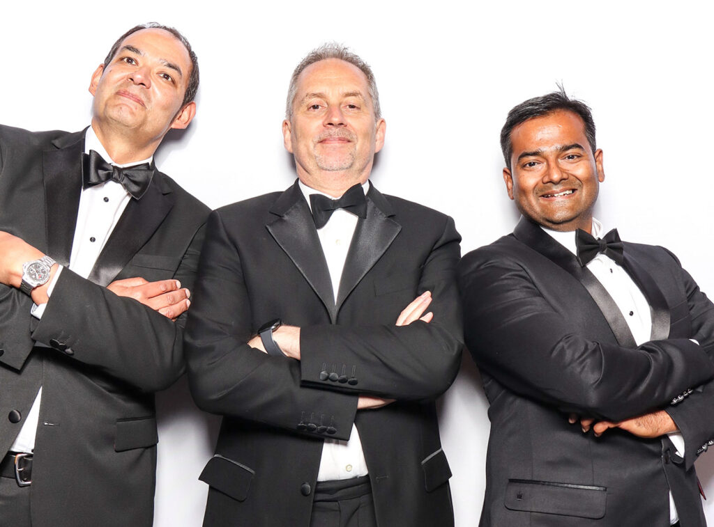 fun classic photo booth image of guests dressed in black tie posing against a white backdrop for a Corporate Photo Booth Hire Oxfordshire 