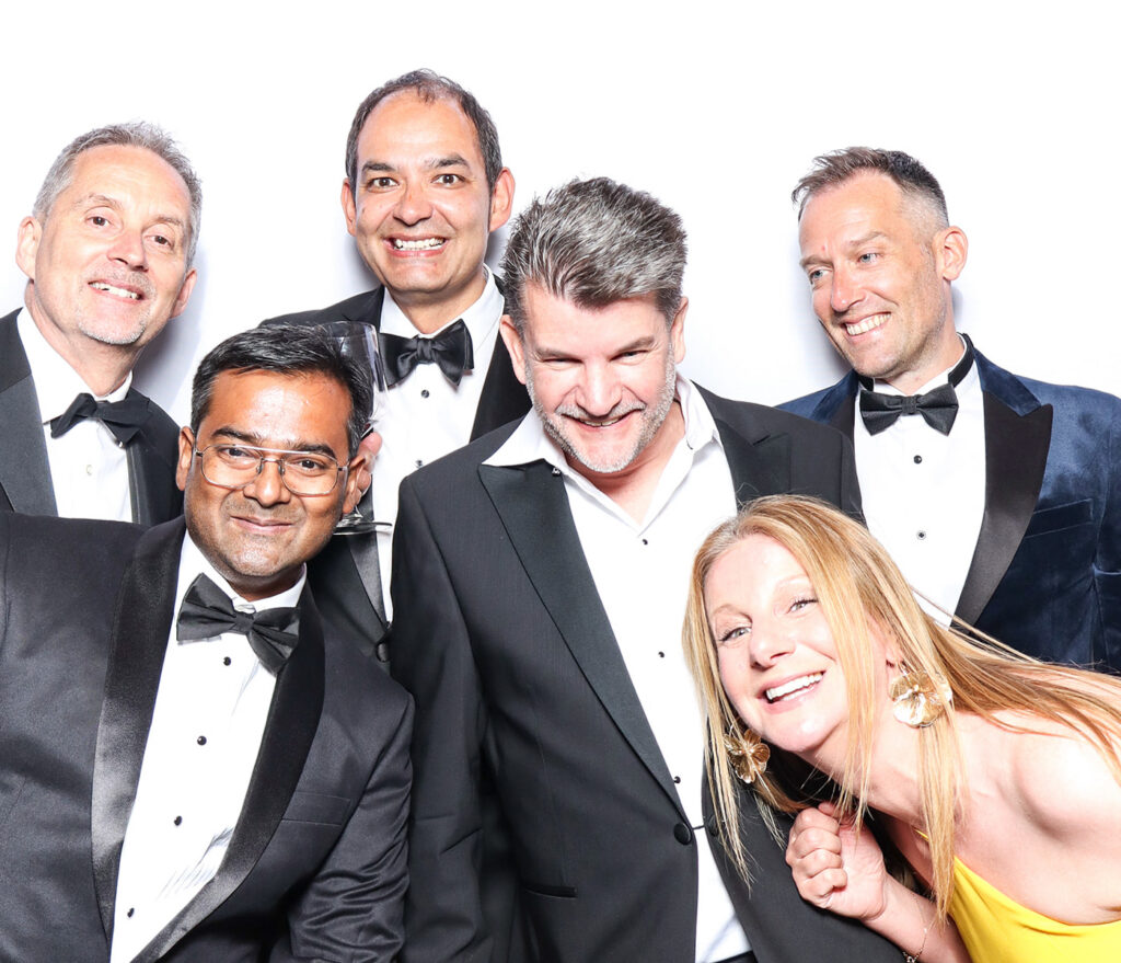 classic image of guests dressed in black tie posing against a white backdrop for a Corporate Photo Booth Hire Oxfordshire 