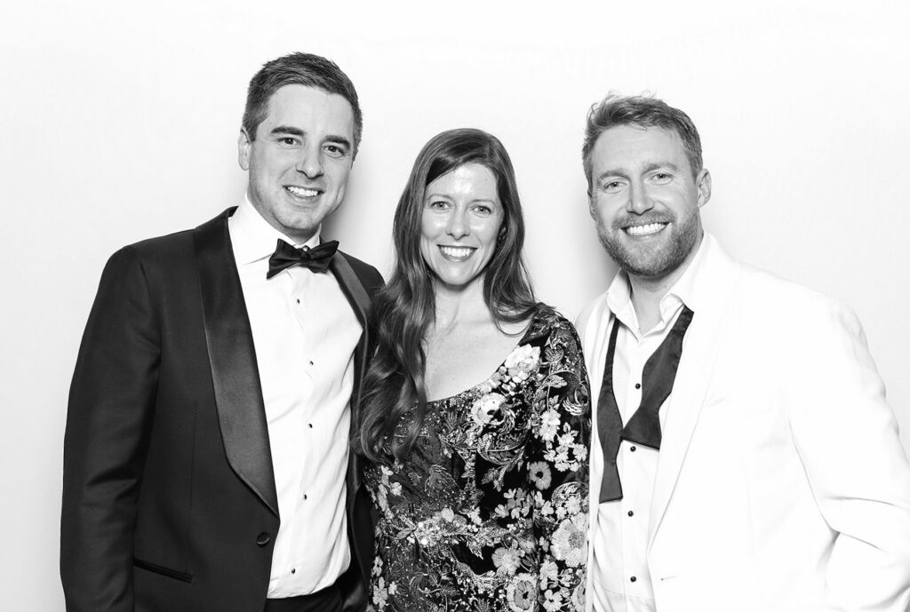 black and white image of 3 guests dressed in black tie posing against a white backdrop for a Corporate Photo Booth Hire Oxfordshire 