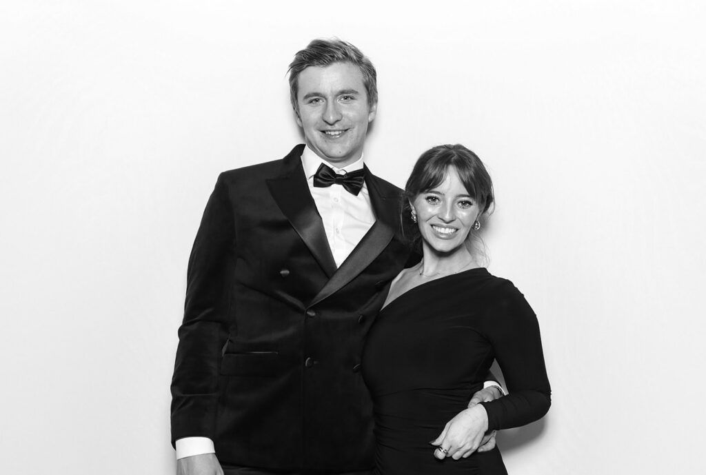 black and white image of 3 guests  posing against a white backdrop for  an awards gala