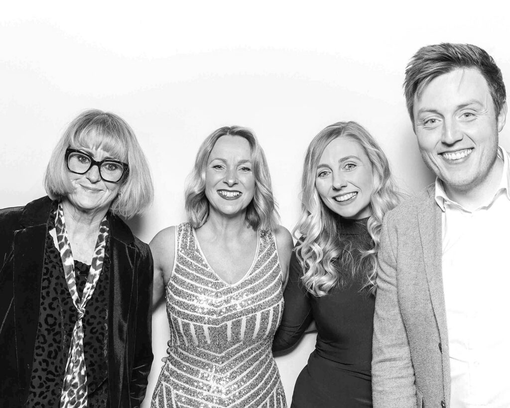 black and white image of 4 guests  posing against a white backdrop for a Corporate Photo Booth Hire Oxfordshire , during an awards gala corporate event