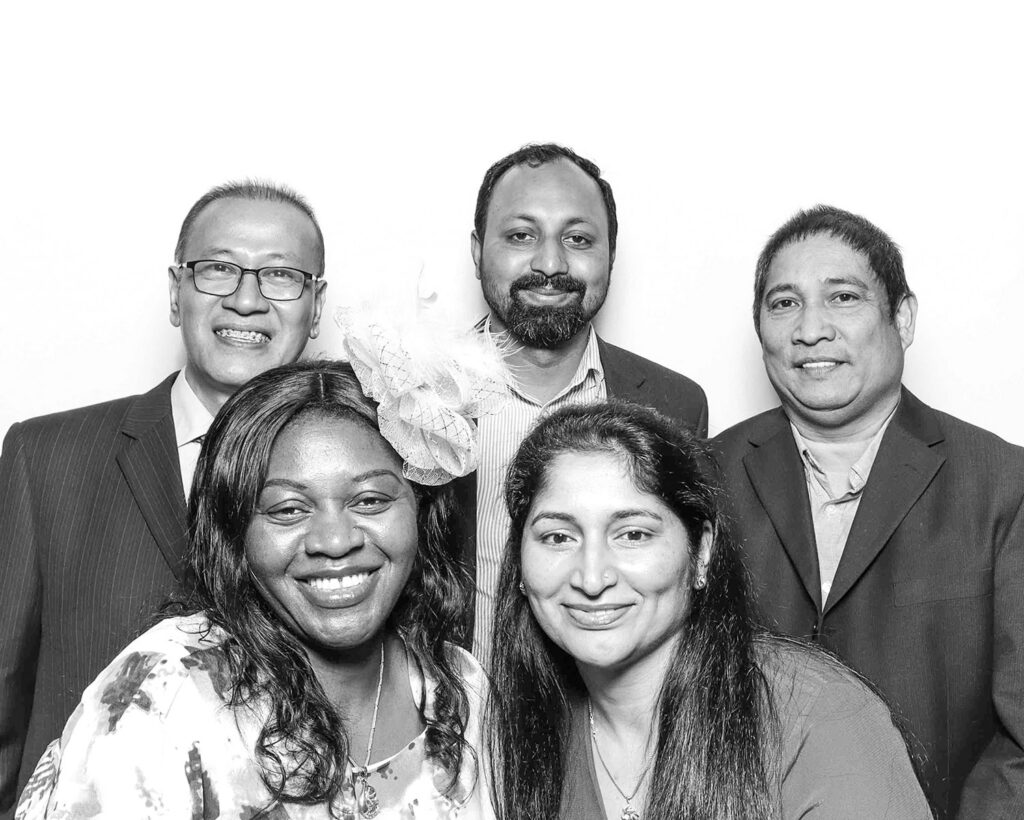 black and white image of guests  posing against a white backdrop for a ballroom gala event
