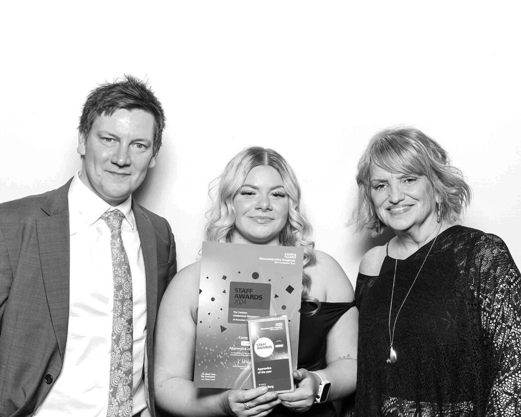 black and white image of 3 guests  posing against a white backdrop for  an awards gala