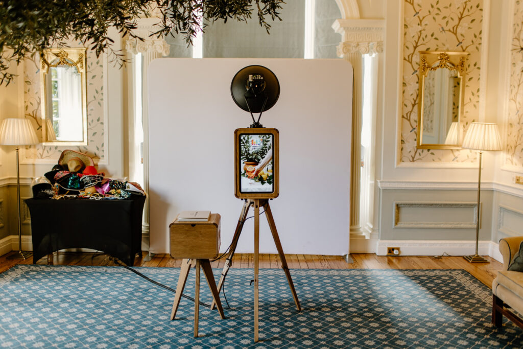 The Icon wooden corporate photo booth set up for an elegant event entertainment with a plain white backdrop and a custom rear screen
