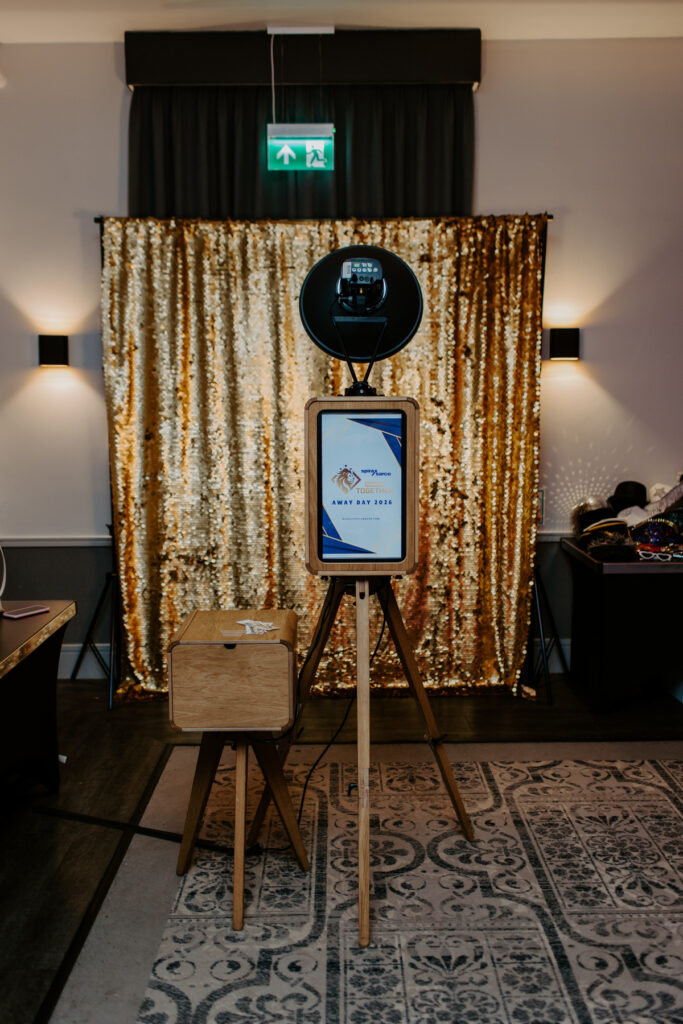 wooden luxury photo booth with a custom rear screen with company logo, during a large corporate event entertainment at De Vere Cotswold Water Park Photo Booth Hire and a gold sequins wall
