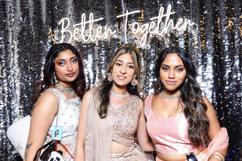 asian guests posing for a photobooth rental, against a silver  backdrop during a 2-day wedding reception entertainment in Wiltshire 