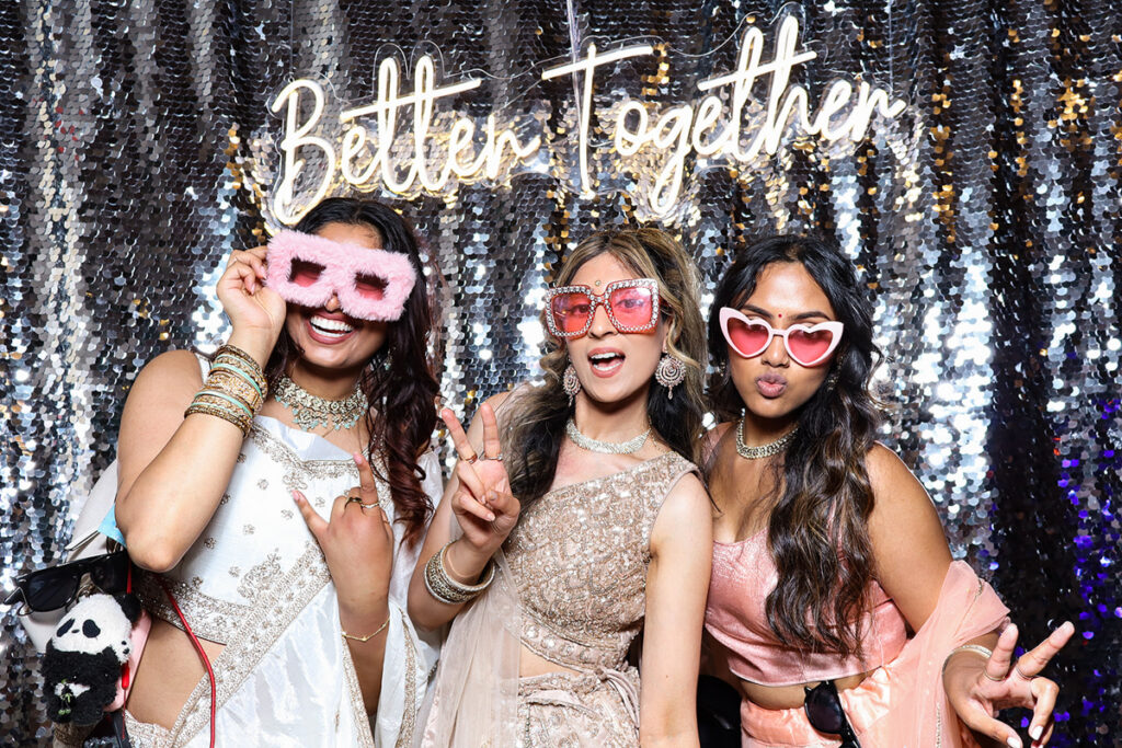asian guests posing for a photobooth rental, against a silver  backdrop during a 2-day wedding reception entertainment in Wiltshire 