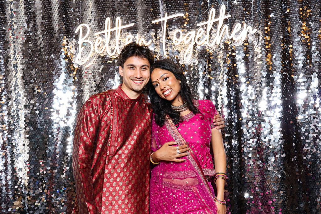 asian guests posing for a photobooth rental, against a silver  backdrop during a 2-day wedding reception entertainment in Wiltshire 