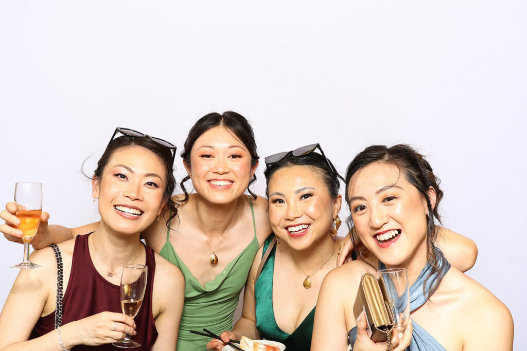 asian guests posing for a photo booth hire, against a white backdrop during a 2-day wedding party entertainment at Grittleton House wedding venue, in Wiltshire 