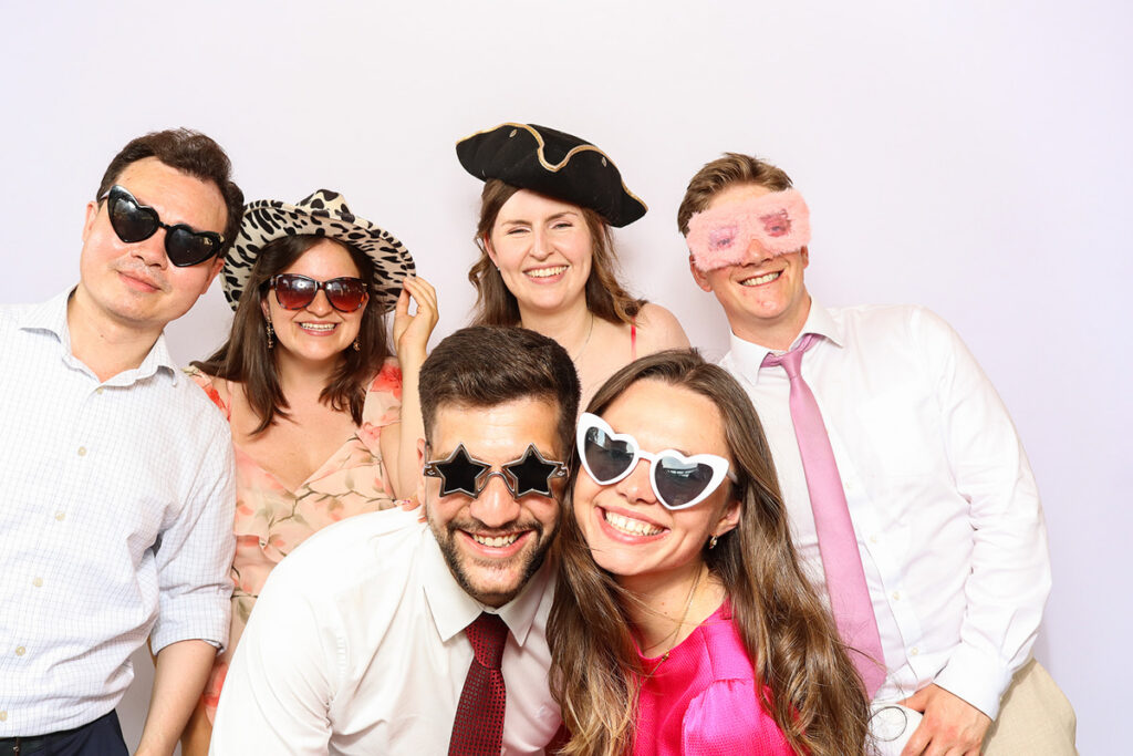 asian guests posing for a photo booth hire, against a white backdrop during a 2-day wedding party entertainment at Grittleton House wedding venue, in Wiltshire 