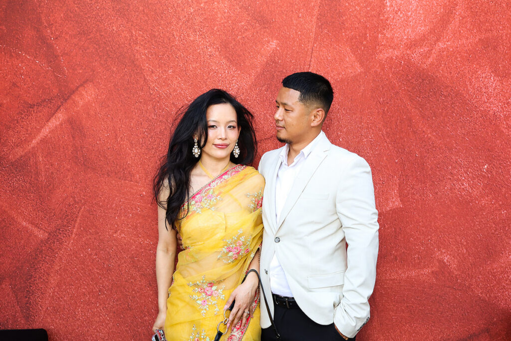 asian guests posing for a photobooth rental, against a maroon backdrop during a 2-day wedding reception entertainment in Wiltshire 