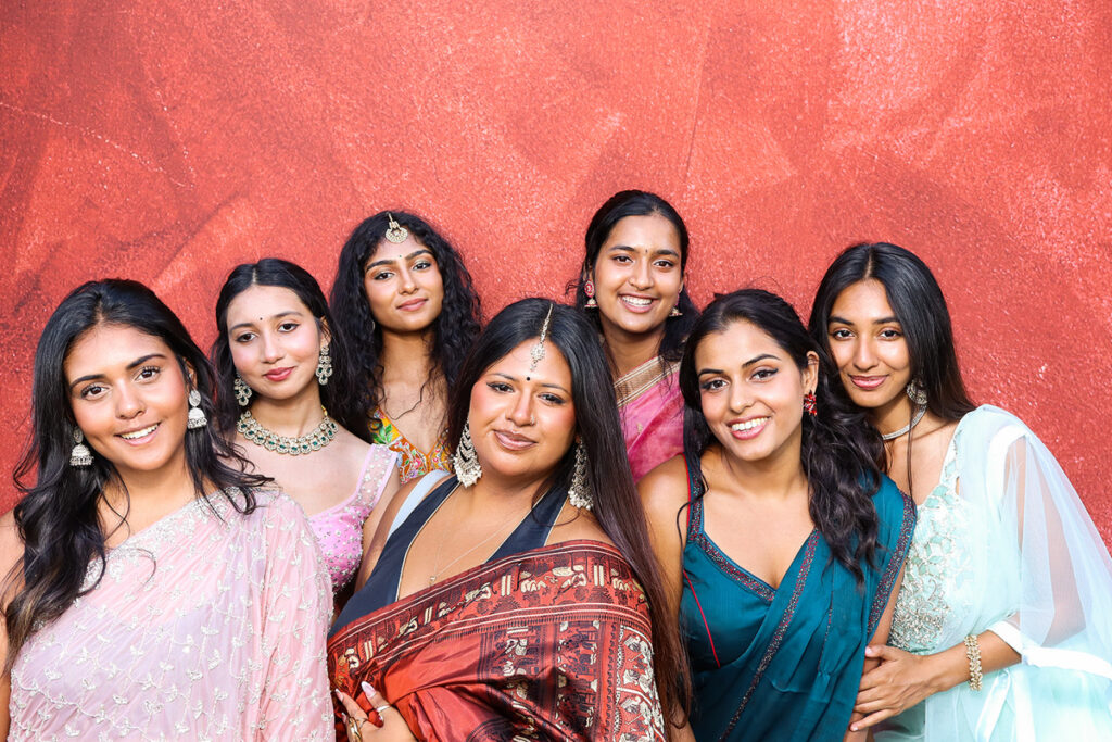 asian guests posing for a photobooth rental, against a maroon backdrop during a 2-day wedding reception entertainment in Wiltshire 