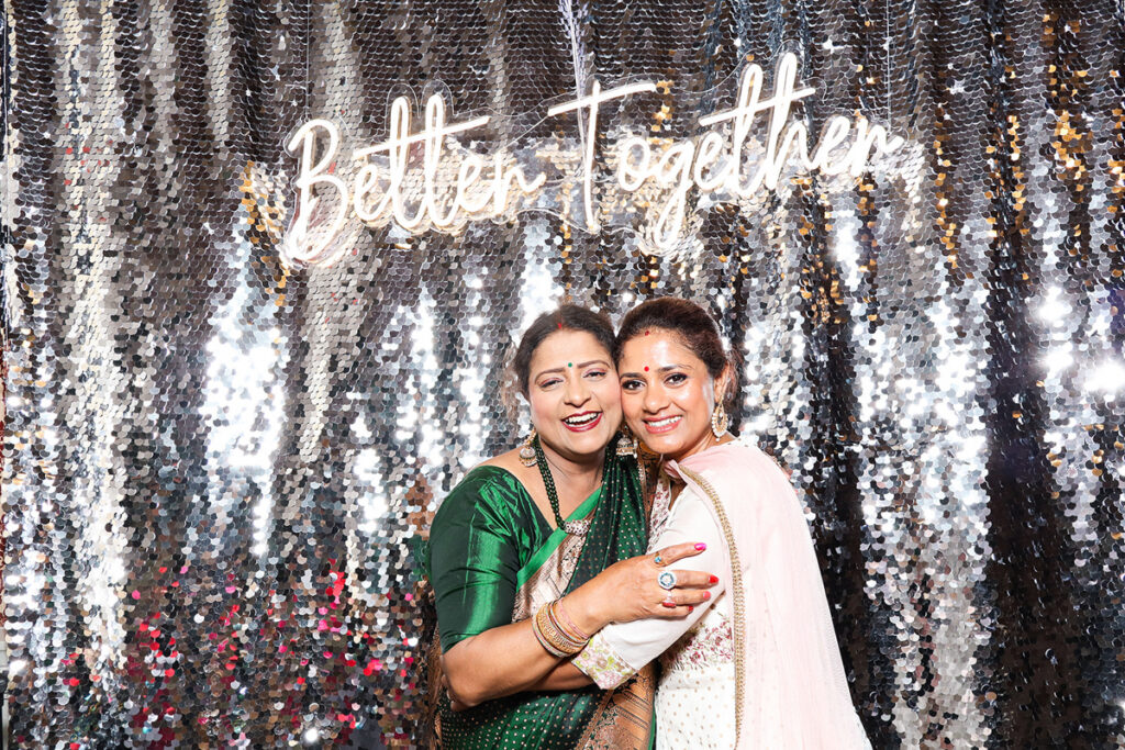 asian guests posing for a photobooth rental, against a silver  backdrop during a 2-day wedding reception entertainment in Wiltshire 