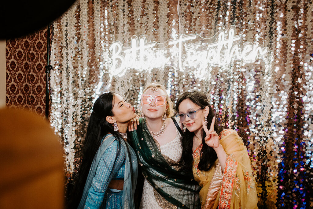 guests posing for a premium wooden photo booth setup with props, and champagne sequins  backdrop for an evening wedding reception party at Grittleton House wedding venue in Wiltshire 
