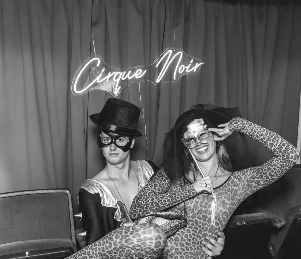 circus themed event photobooth with a vintage b&w style prints of guests posing against a circus style backdrop and themed props