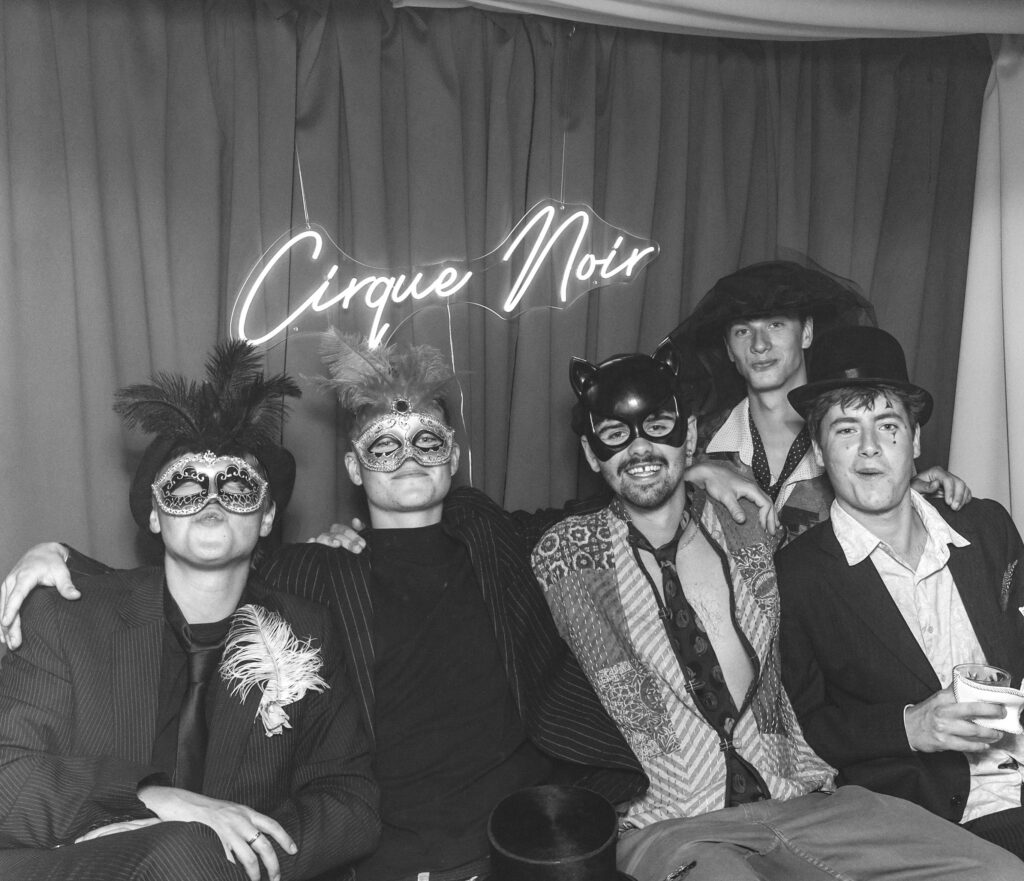 circus themed event photobooth with a vintage b&w style prints of guests posing against a circus style backdrop and themed props