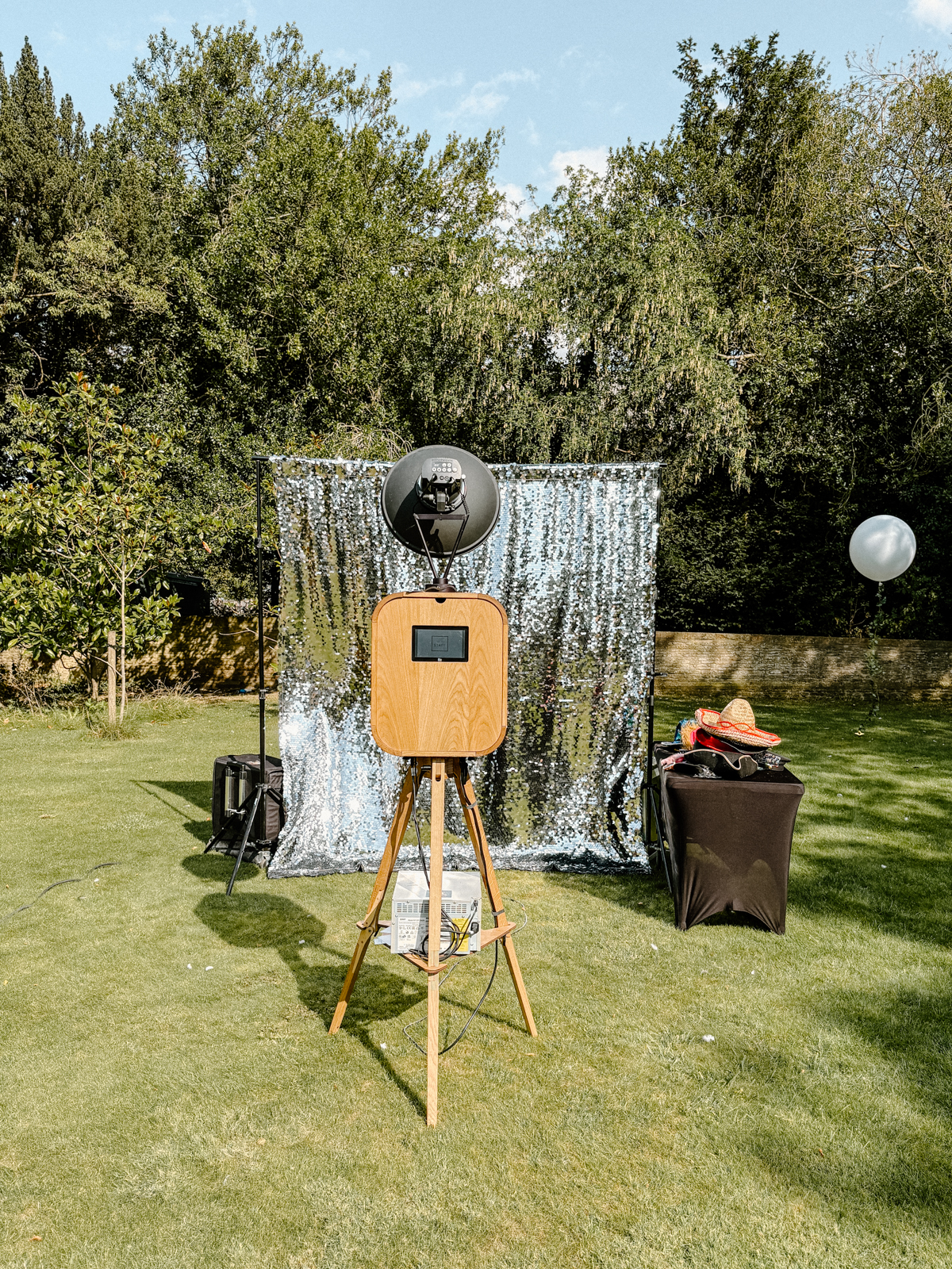Outdoor wooden photo booth with silver sequin backdrop at a private birthday party at Soho Farmhouse.