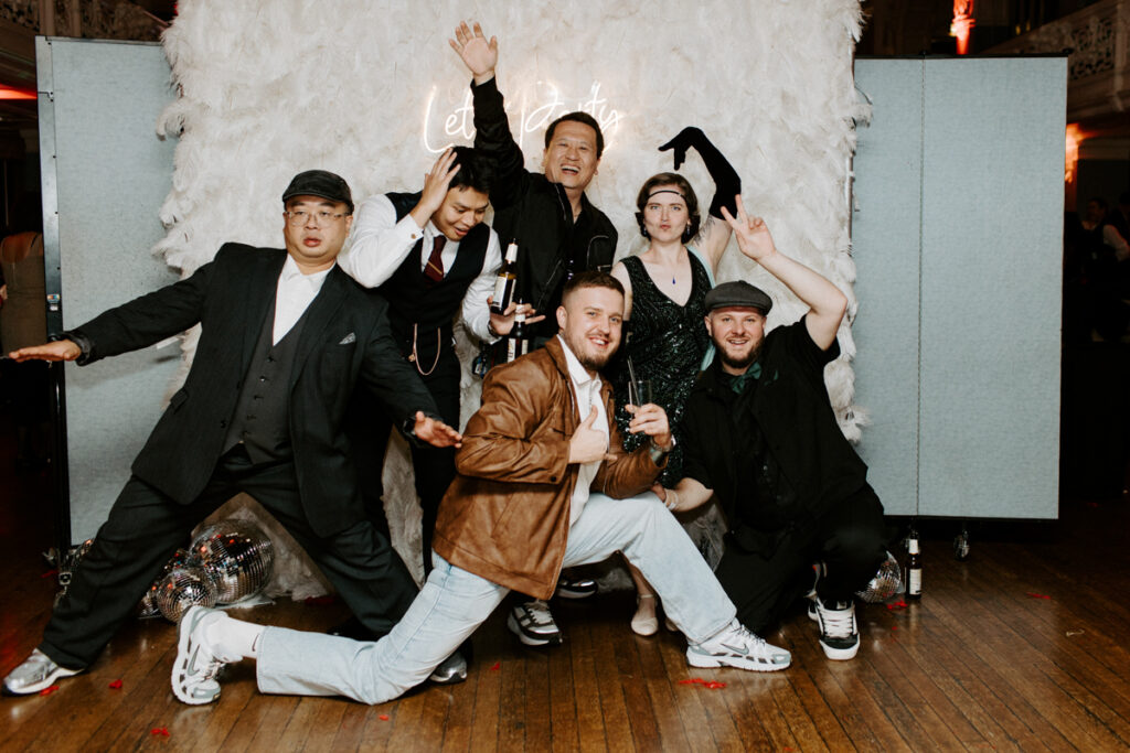 large group of guests posing at Oxford Town Hall during a private party event for Kibou restaurant team party , posing against white feather walls with Let's Party Neon Hire