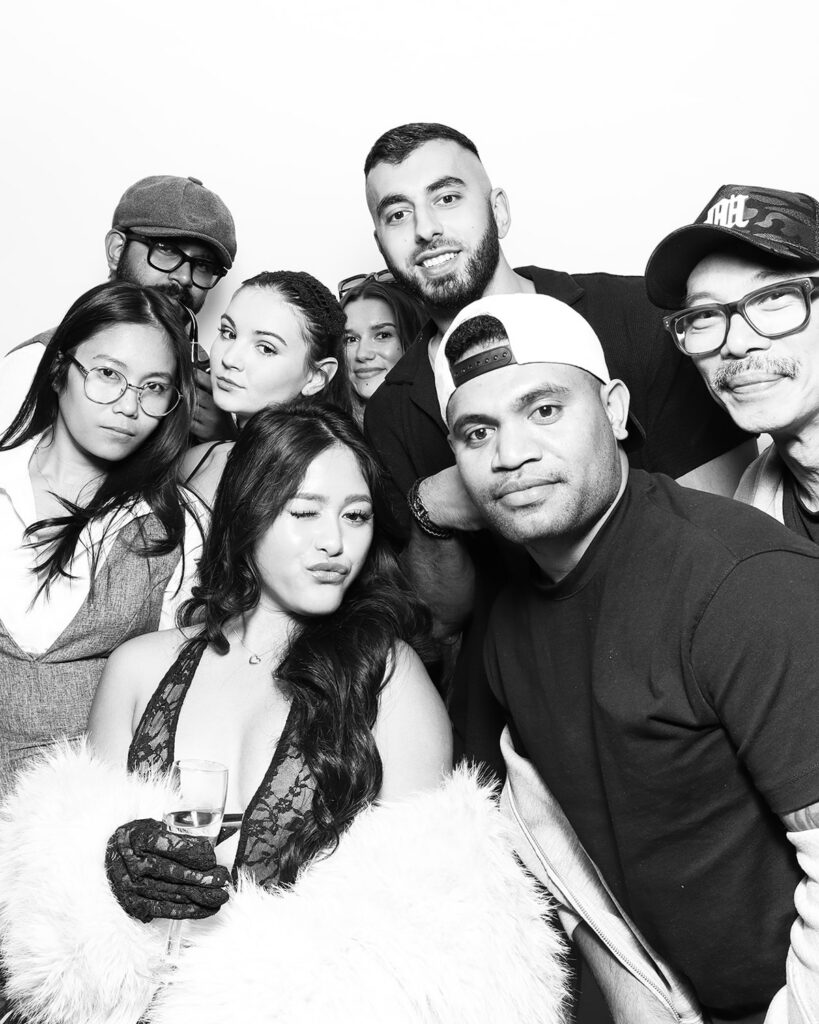 b&w image of large group of guests posing against a white backdrop, during a corporate event party entertainment with mad hat photo booth hire in oxfordshire