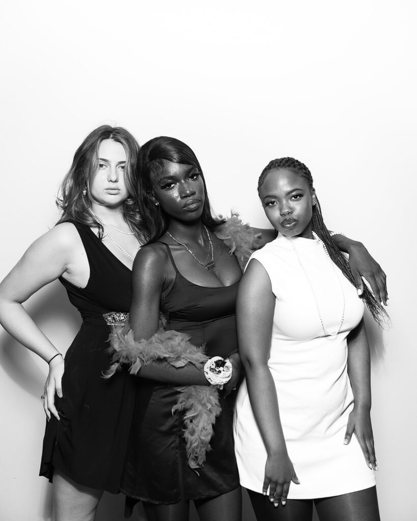 b&w image of 3 guests posing against a white backdrop, during a corporate event party entertainment with mad hat photo booth hire in oxfordshire