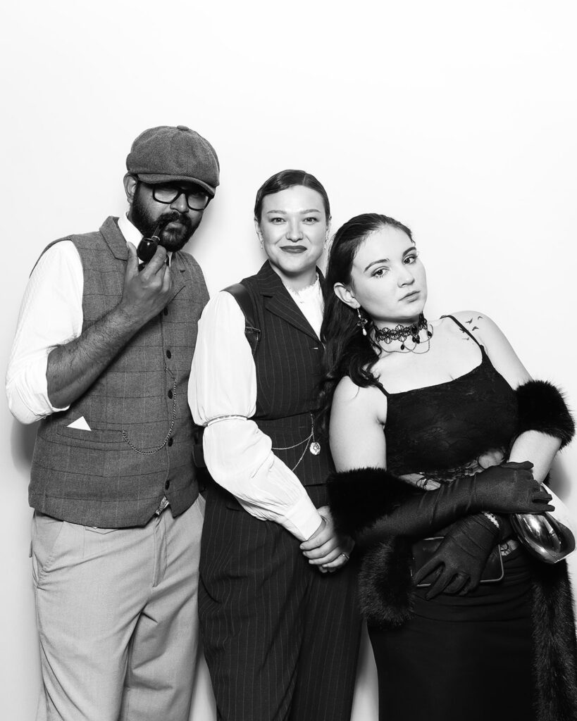 b&w image of 3 guests posing against a white backdrop, during a corporate event party entertainment with mad hat photo booth hire in oxfordshire