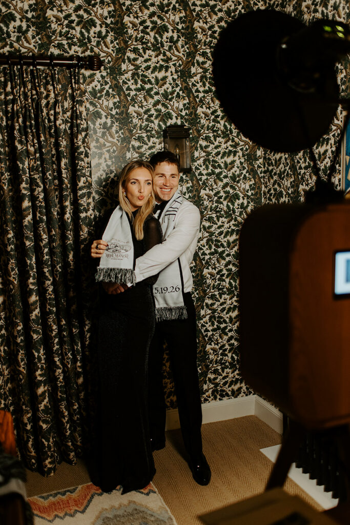 couple posing against a wallpaper wall during a A Vogue-Featured Wedding After-Party at Coombe End Manor, Cheltenham with a Vintage Photo Booth Hire