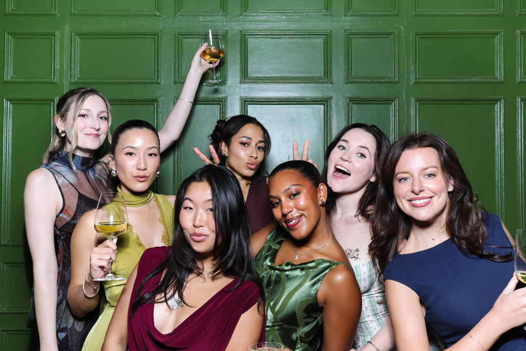 large group of guests posing against a photo booth for a wedding reception party 