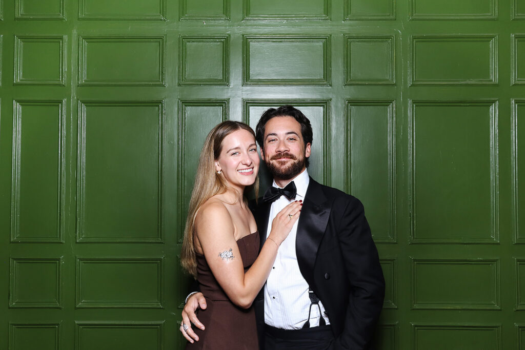 2 guests posing against a photo booth for a wedding reception party at dumbleton hall
