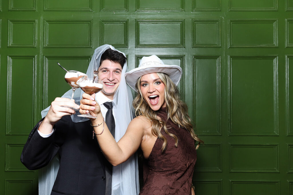 2 guests posing against a photo booth for a wedding reception party 