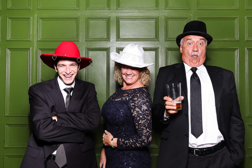 guests posing against a green wall during a wedding reception party at dumbleton hall 
