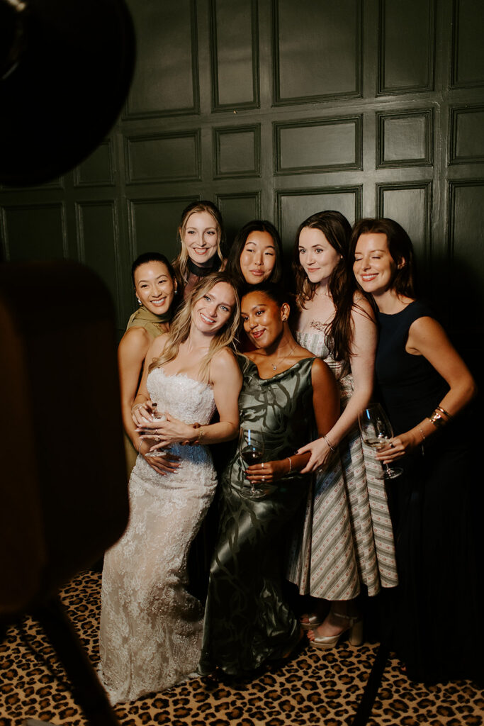 guests and bride posing against a photo booth for a wedding reception party 